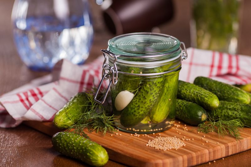Банка с плотно уложенными огурцами, чесноком и укропом на доске