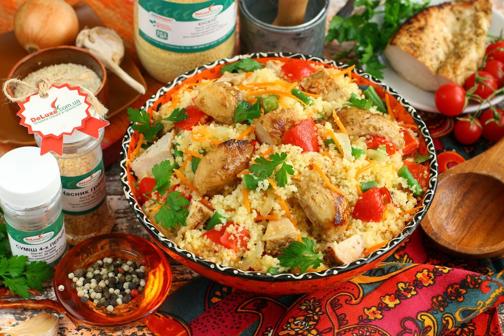 Кус-кус зі шматочками курки, морквою і спаржевою квасолею в керамічній мисці