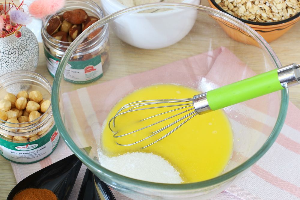 Растопленное сливочное масло с сахаром в стеклянной миске с венчиком