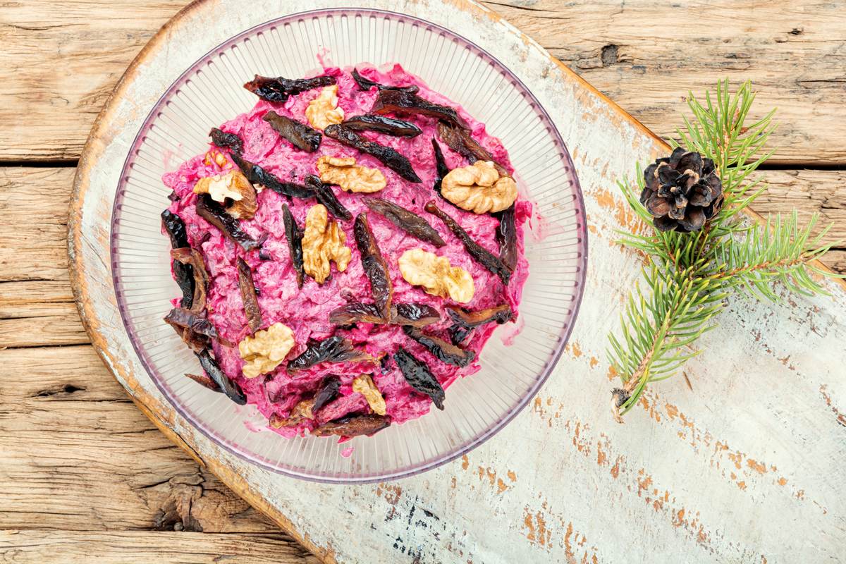 Тёртая варёная свёкла с черносливом соломкой и половинками грецких орехов в стеклянной миске