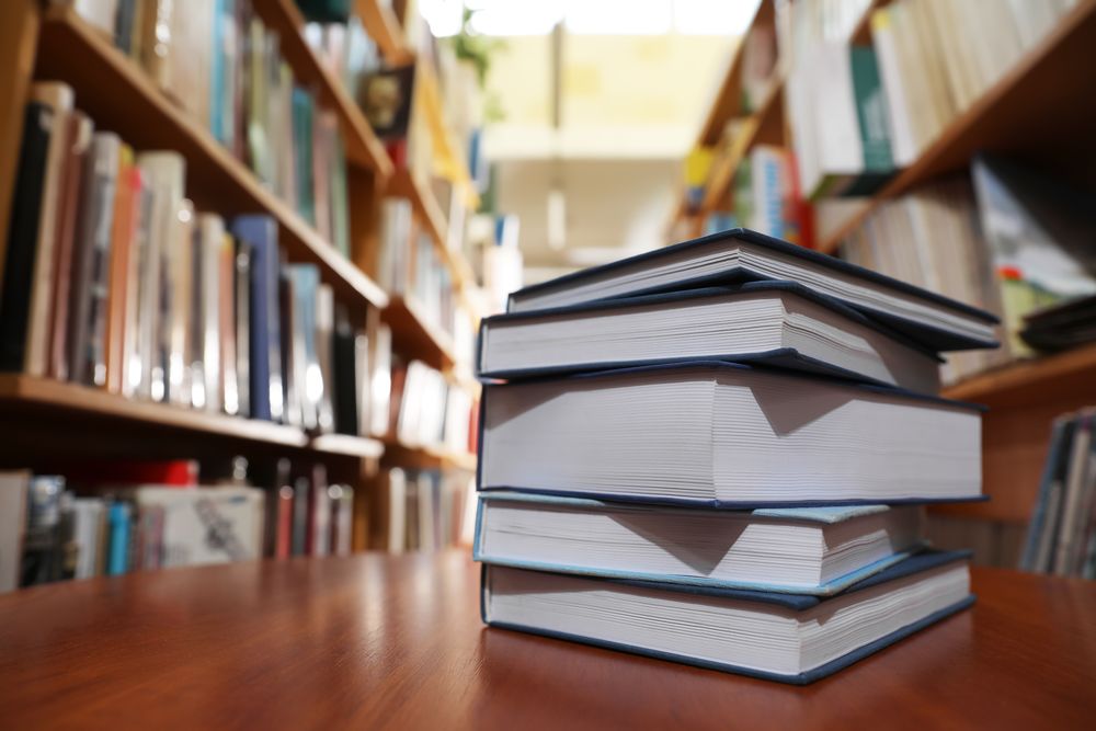 Стос товстих книг на дерев'яному столі в бібліотеці