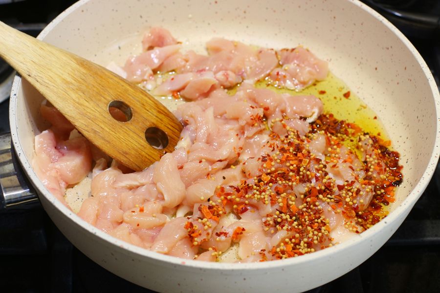 Куриное филе соломкой на сковороде, посыпанное смесью специй
