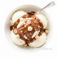 Ванильное мороженое с ореховым соусом и фундуком в белой миске