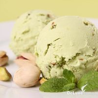 Два шарика фисташкового мороженого с орехами в скорлупе и листьями мяты