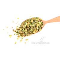 Дроблёная очищенная фисташка в деревянной ложке на белом фоне