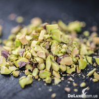 Кусочки дроблёной фисташки крупным планом на тёмном фоне